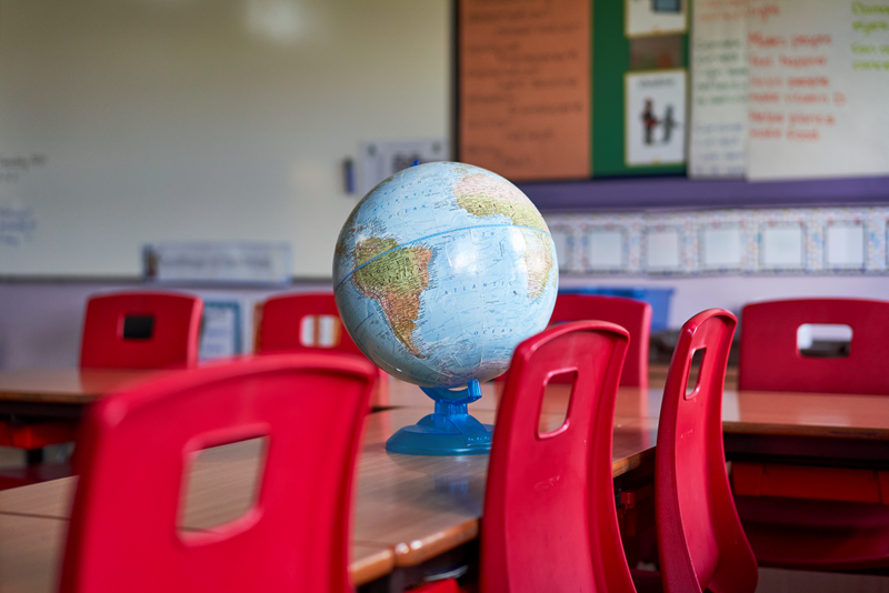 Globe on desk in empty classroom