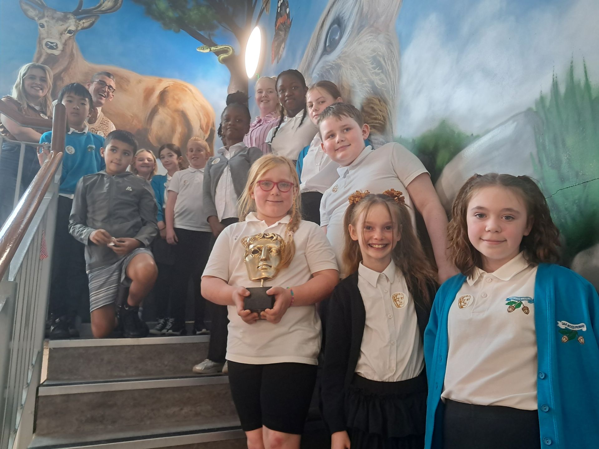 Oakwood Primary students holding the bafta mask with guests
