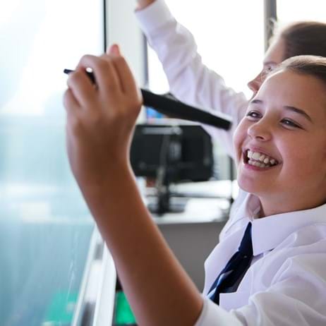 Girl smiling writing on school whiteboard