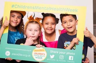 primary school-aged children in fancy dress standing in a Children's Mental Health Week selfie frame