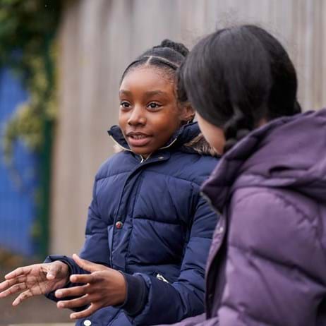 Two children sitting in a playground, chatting