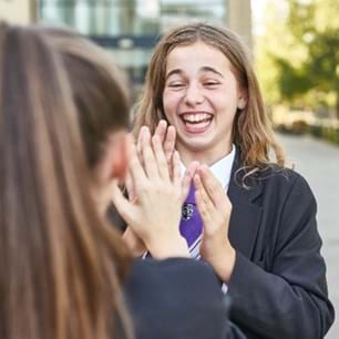 Girl smiling in playground playing a game with a friend. Other children in background