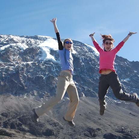 Two people jumping in the air in front of Kilimanjaro