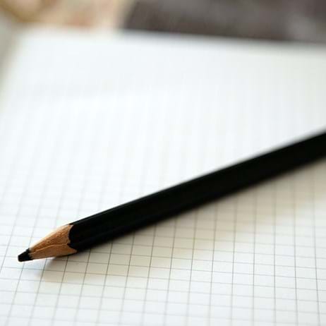 A pencil in a squared notebook, in a classroom