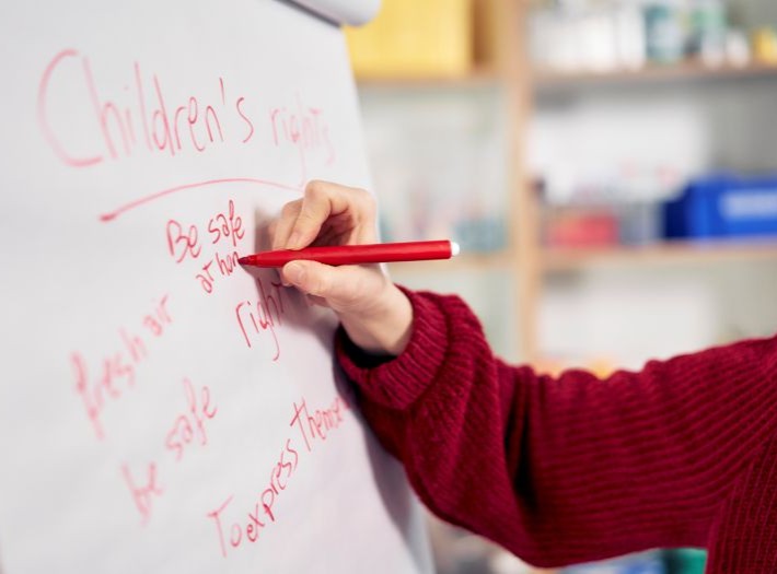 An adult is writing on a big piece of white paper as part of a training session