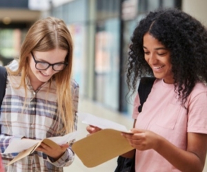 Three teenage girls happily opening their exam results