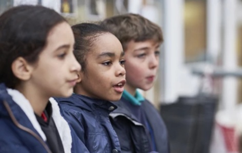 Three primary aged pupils standing outside the classroom