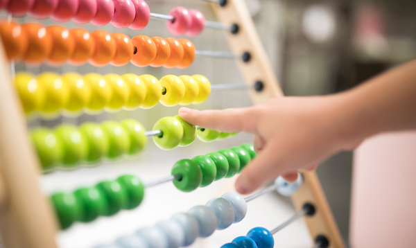 Child's hand playing with brightly coloured abacus