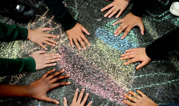 children putting their hands on a heart drawn in chalk on a playground