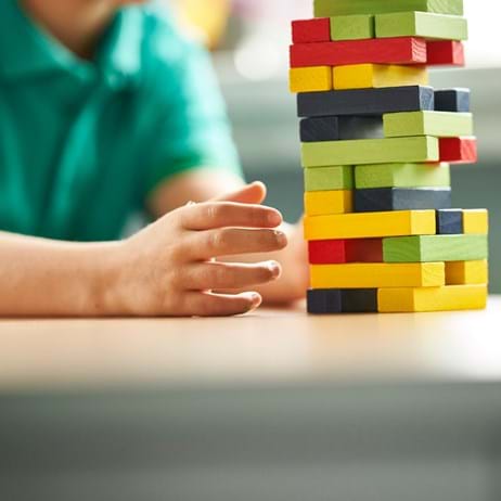 Child's hand playing with colourful building blocks