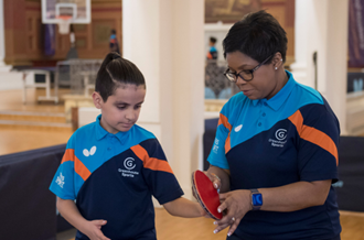 A woman and a child preparing to play table tennis