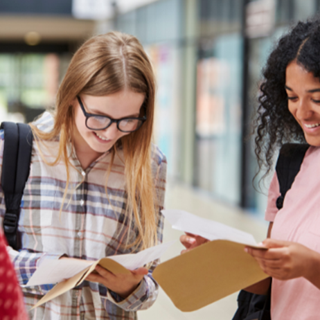 Three female students smiling looking at their results on paper