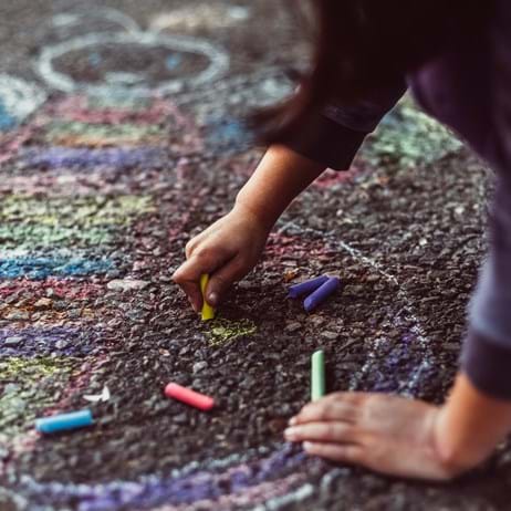 Child drawing with chalk in school playground