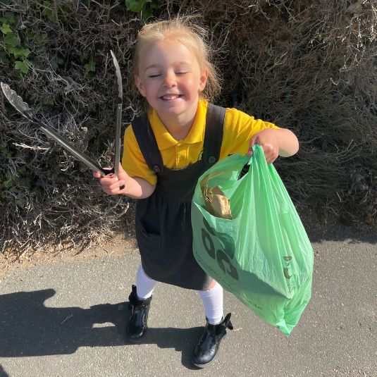 young girl with tongs and a bag showing the litter she's picked up