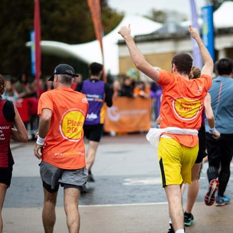Place2Be runners with one holding hands in the air