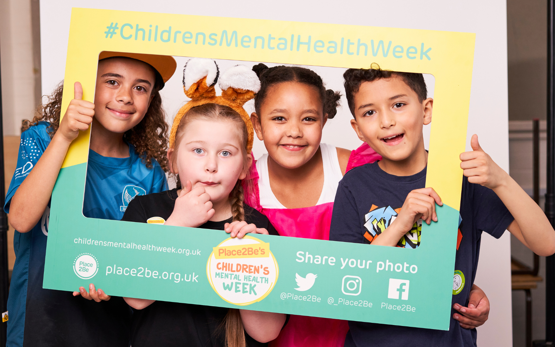 primary school-aged children in fancy dress standing in a Children's Mental Health Week selfie frame