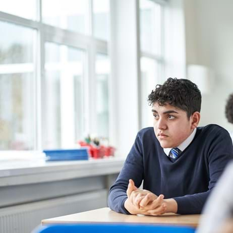 Boy sitting in a classroom looking out the window