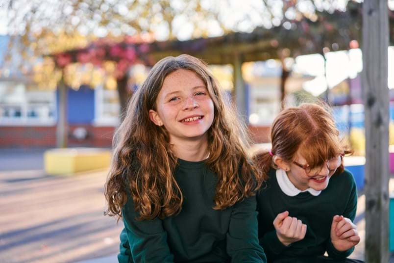 Young girl laughing with her friend outside