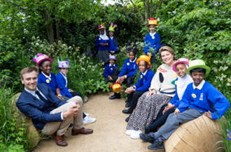 Pupils, Jamie and Kate Silverton sat on the garden wearing top hats