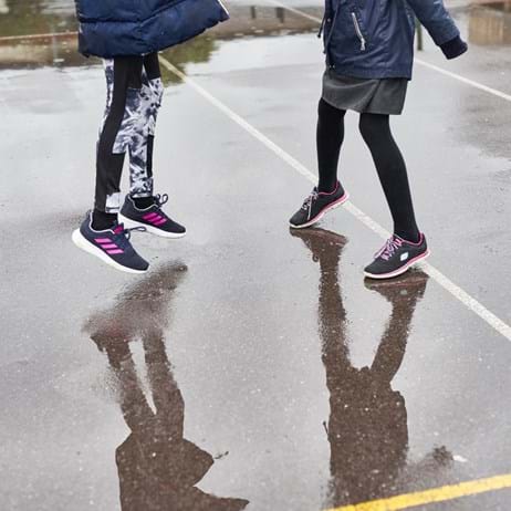Children's feet jumping in puddles in playground