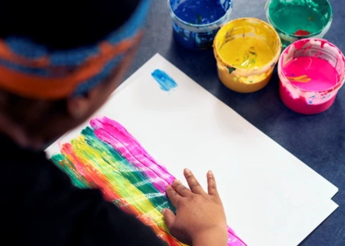 trainee child counsellor experimenting finger painting on paper with brightly coloured paints